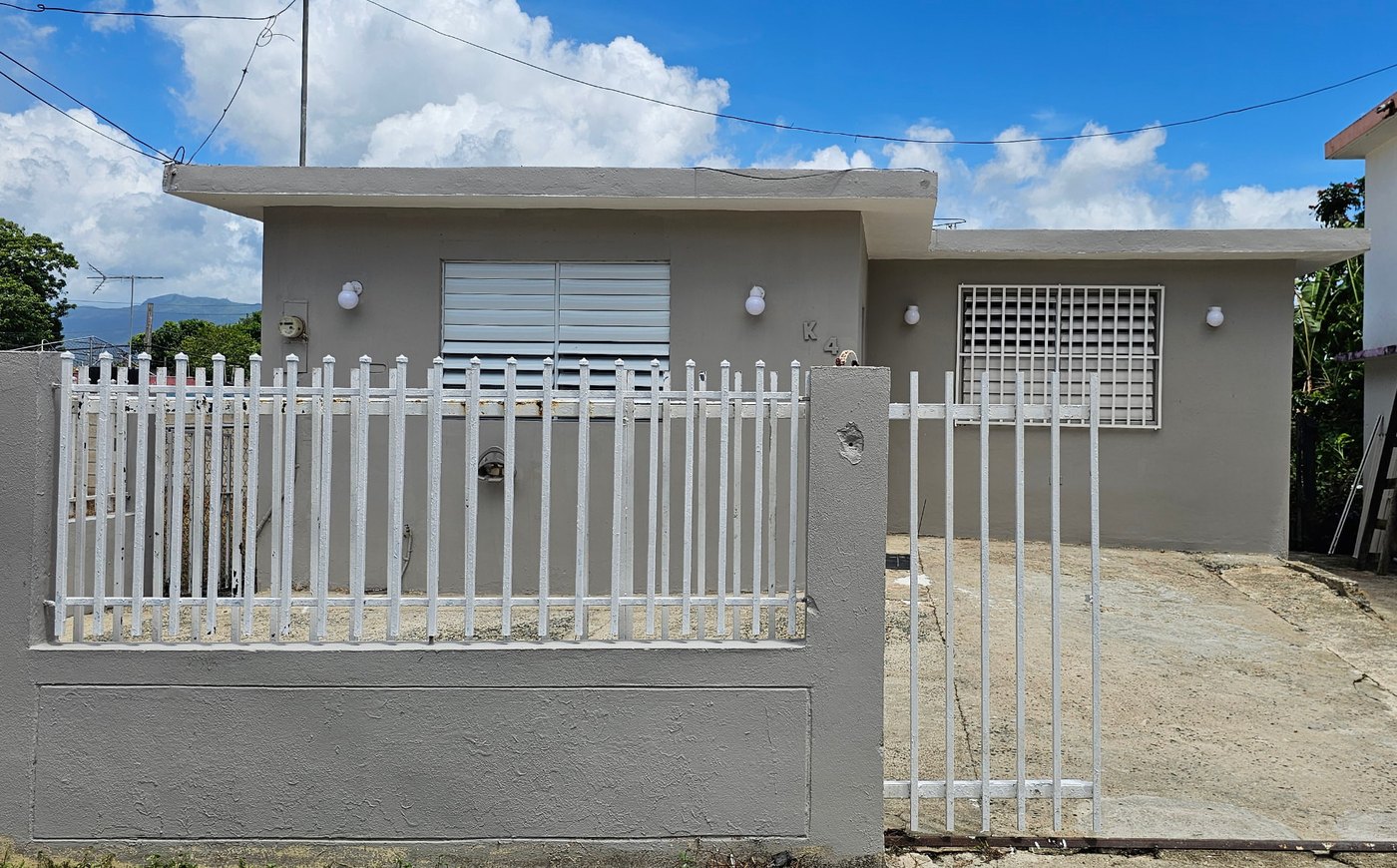 Exterior of a renovated single-family home with a white picket fence in Puerto Rico